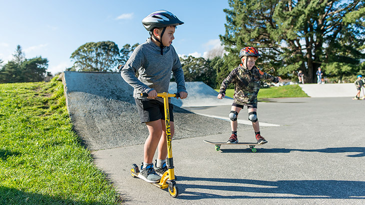 Kids playing on scooters with helmets on heads