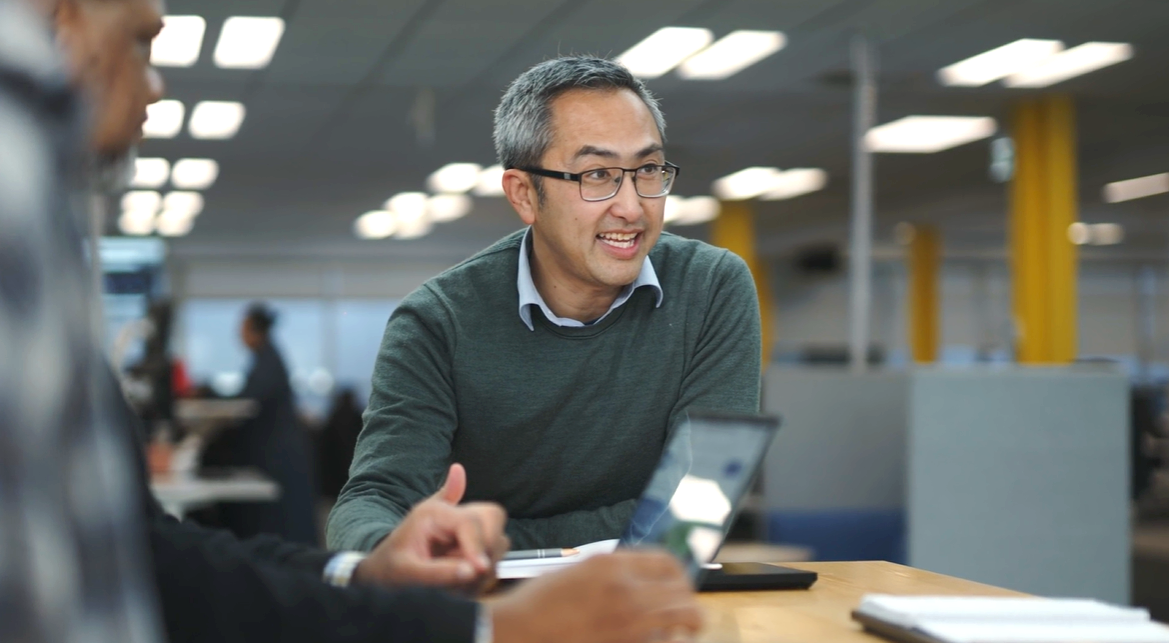 Leon standing at a high table chatting with colleagues 