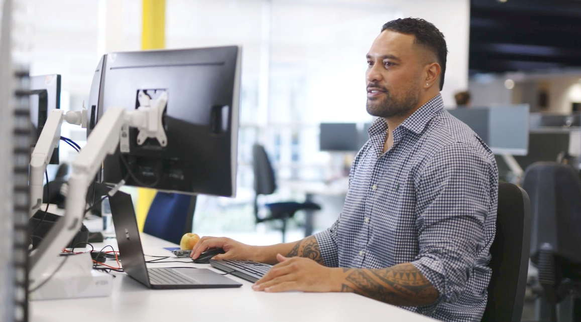 Tux sitting at a desk working on a computer