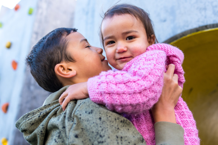 A young boy holds his baby sister