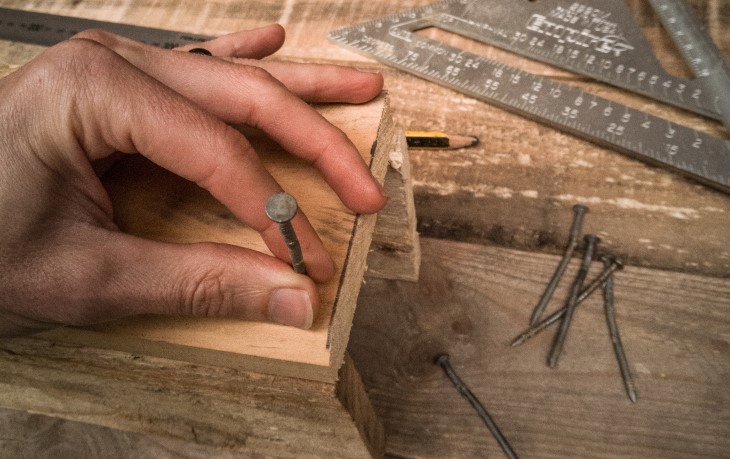 Hand holds nail in place