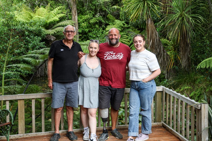 Derek and his father smile for a photo in the woods with Derek's two teenage daughters