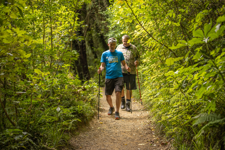 Andrew Leslie and George Thompson using their walking sticks to walk on a path in the bush. 
