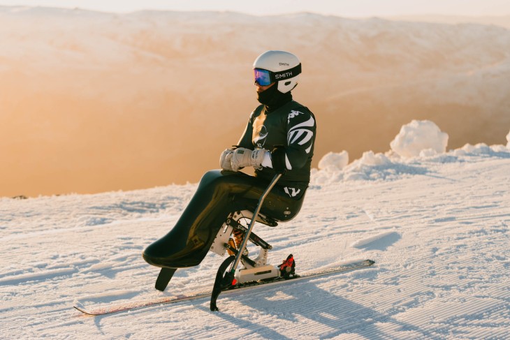 Corey Peters on his sit-ski at the top of a snow-covered mountain.