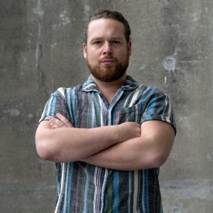 A close-up photo of Luke Hollis with his arms folded.