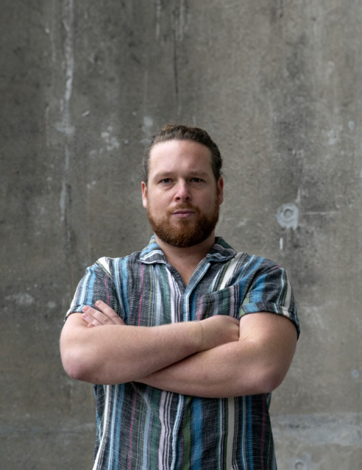 A close-up photo of Luke Hollis with his arms folded.