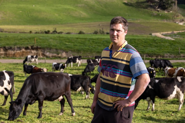 Mark Julian standing in a paddock in front of a herd of cows.