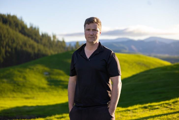 Mark Julian standing on his farm with hills in the background.
