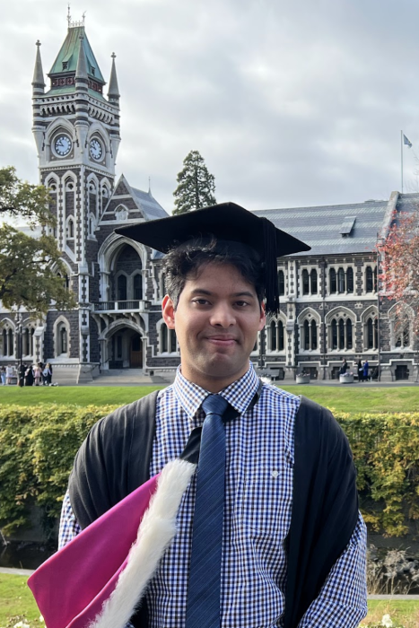 Merrick Rodrigues posing for a photo in his graduation clothing.