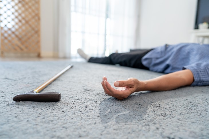 An older man lying on his back on the floor after suffering a fall.