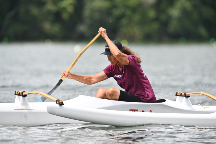 Raipoia Brightwell paddling in her waka ama canoe on the water.