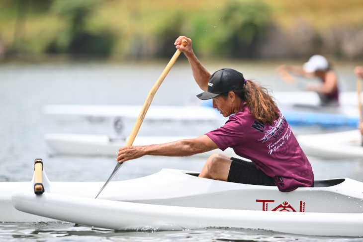 Raipoia Brightwell paddling in her waka ama canoe on the water.