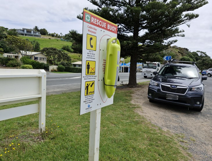 A rescue buoy mounted on a sign with instructions on how to use it. 