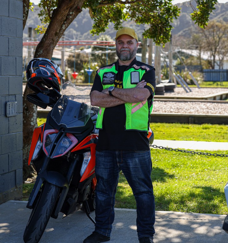 Steve Davies standing next to his motorbike with his arms folded.