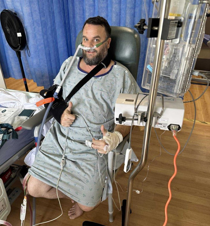 Steve Davies sitting in hospital giving the thumbs up.