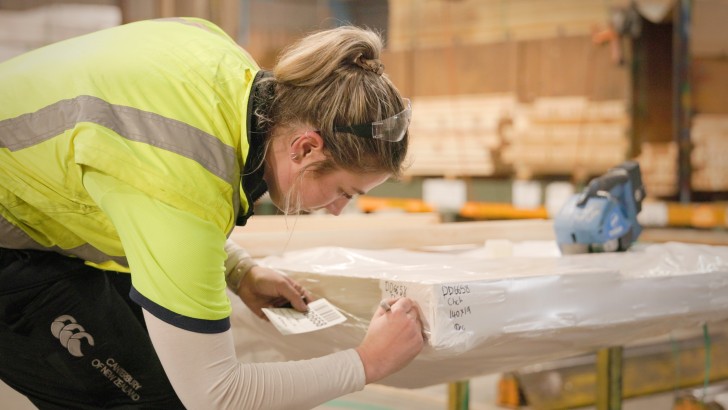 A woman marking pieces of timber at Westco Lumber.